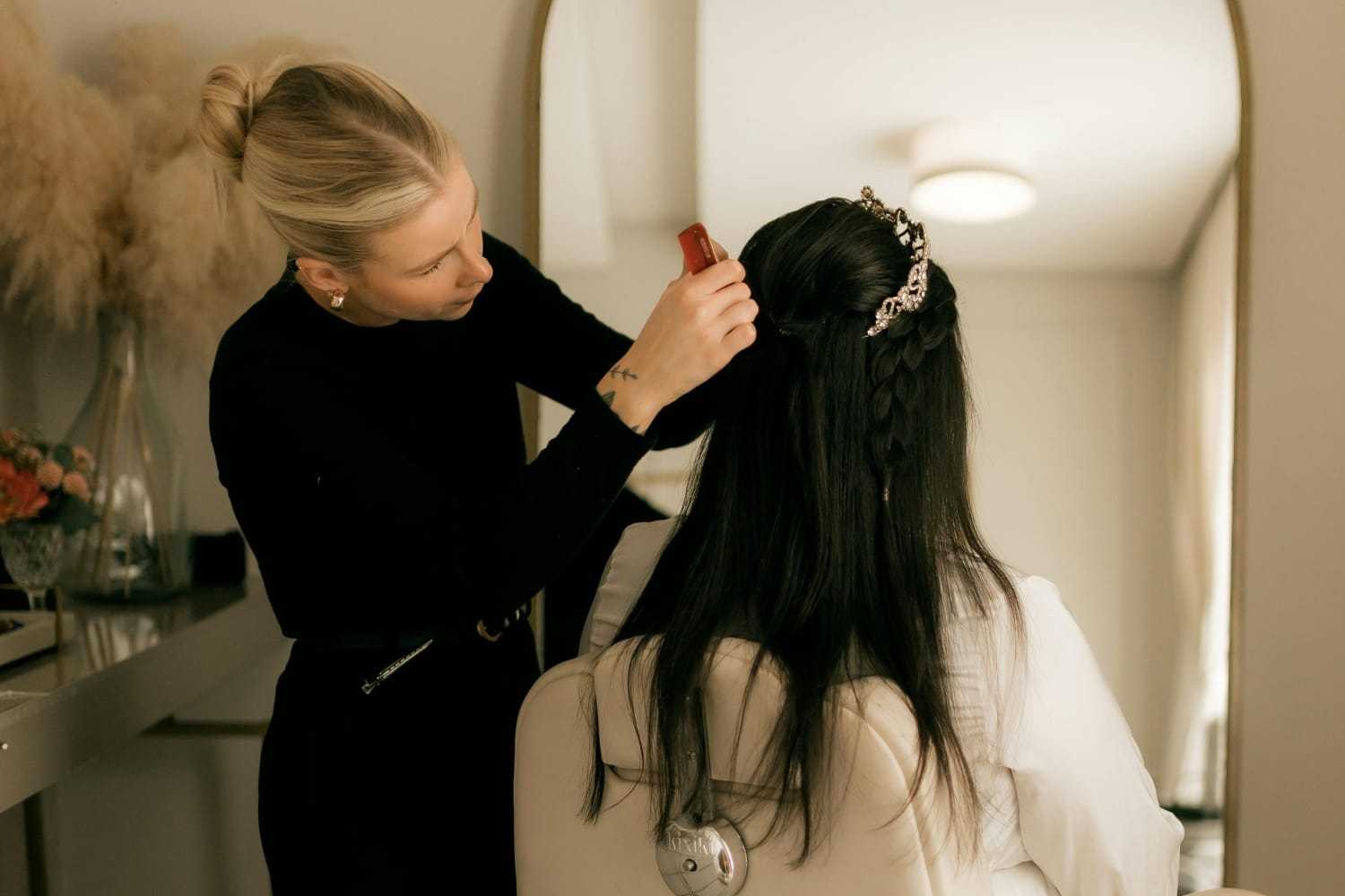 Hairdresser styling a woman's hair with an elegant hairpin in a salon.